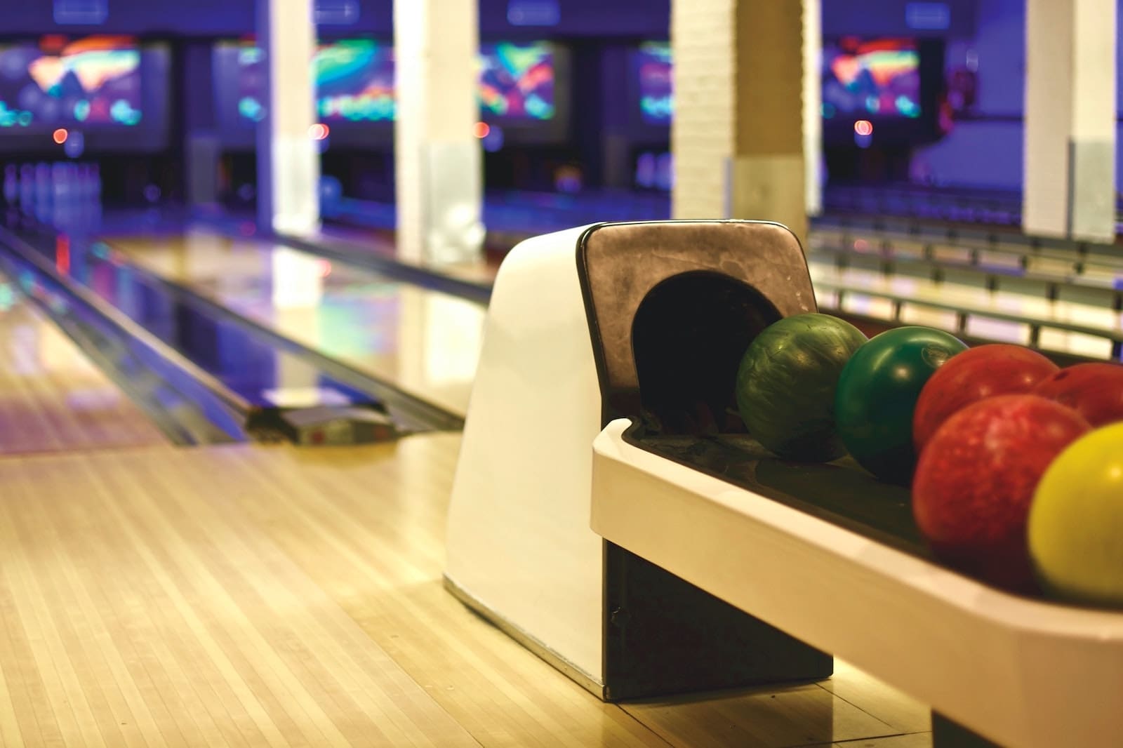 image of a bowling alley, with the ball return in the foreground and the bowling pins in the background.